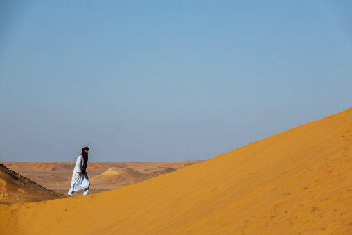 Tuareg man walking along a sand dune ridge, North Africa, Ghardaia, Algeria
