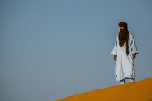 Tuareg man standing at the top of a sand dune, North Africa, Ghardaia, Algeria