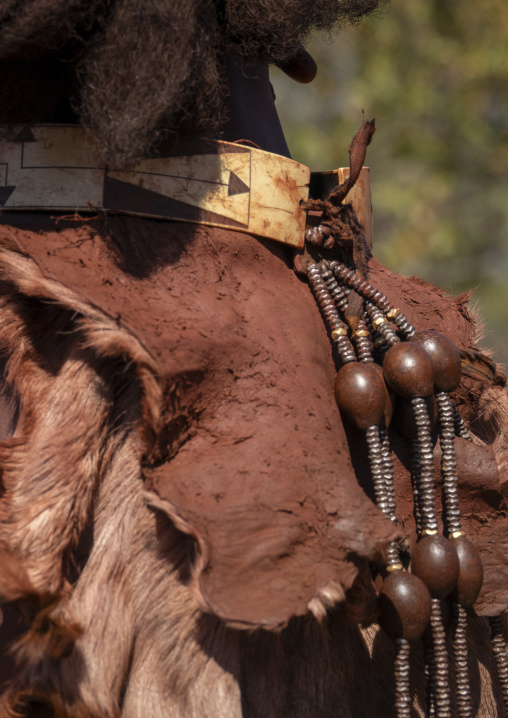 Close-up of a woman's shoulder wearing a carved bone choker and a leather cape with beaded tassels, Cunene Province, Oncocua, Angola