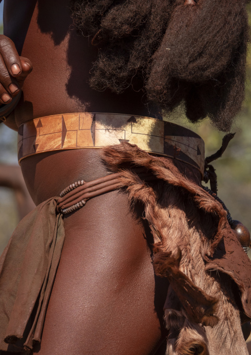 Close-up of a woman's waist wearing a carved patterned belt over a beaded band and goat fur skirt, Cunene Province, Oncocua, Angola