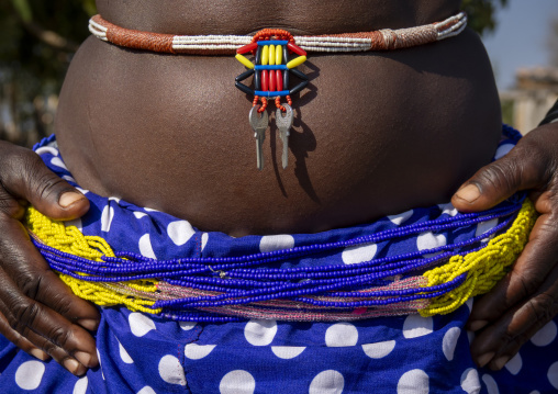 Close-up of a woman's belly wearing a beaded belt with a diamond-shaped amulet and hanging keys, Cunene Province, Cahama, Angola