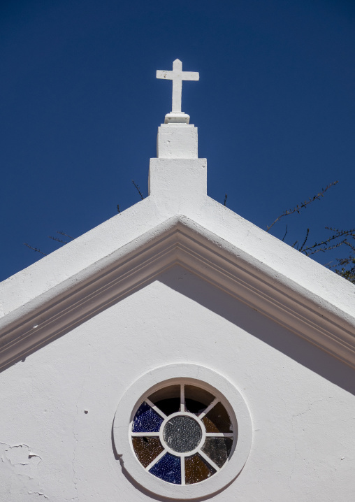 White chapel gable topped with a cross above a round stained-glass window, Huila Province, Lubango, Angola