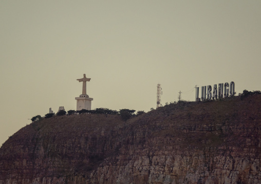 Distant view of the Cristo Rei statue and the LUBANGO sign standing together atop the cliff, Huila Province, Lubango, Angola