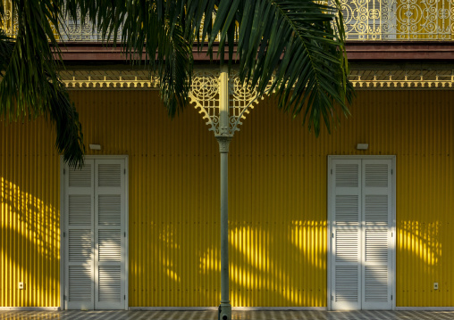 Cast-iron column beneath a palm frond flanked by two shuttered doors on the yellow facade of the Palacio de Ferro, Luanda Province, Luanda, Angola