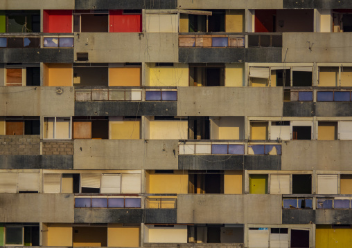 Weathered concrete balconies with colorful doors and broken windows cover the facade of an abandoned apartment building, Luanda Province, Luanda, Angola
