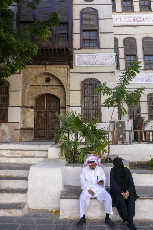 Couple sitting in front of a historic house, Mecca province, Jed