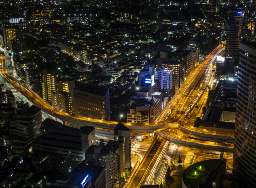 Aerial night view of Tokyo skyscrapers above a curving highway i