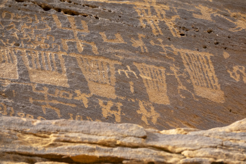 Ancient inscriptions carved in rows on a sandstone cliff, Al Mad