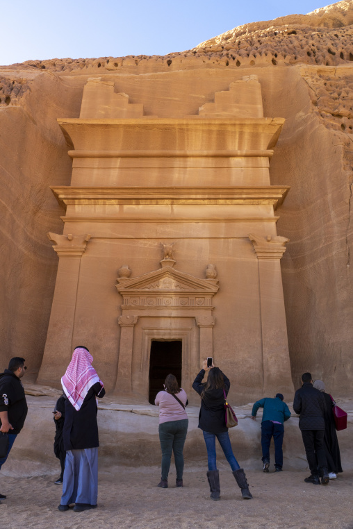 Tourists photographing a Nabataean tomb facade at Hegra, Al Madi