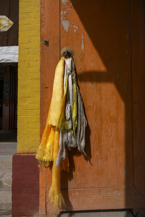 Yellow and white silk scarves hang from a door at Shachong monastery, Qinghai Province, Wayaotai, China