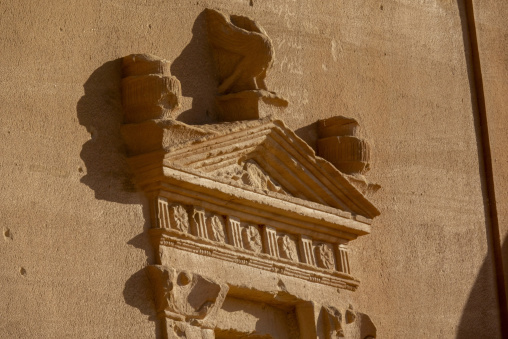 Weathered pediment with rosette carvings on a Nabataean tomb at