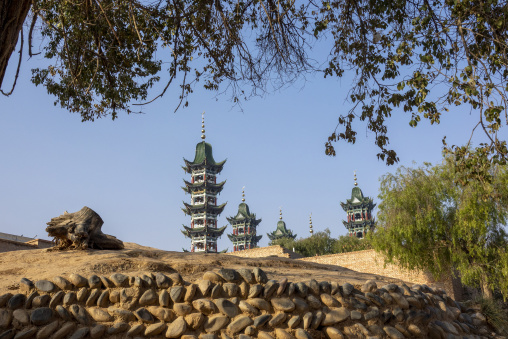 Chinese-style minarets of the Salar people's grand mosque rise above a stone wall, Qinghai Province, Xunhua, China