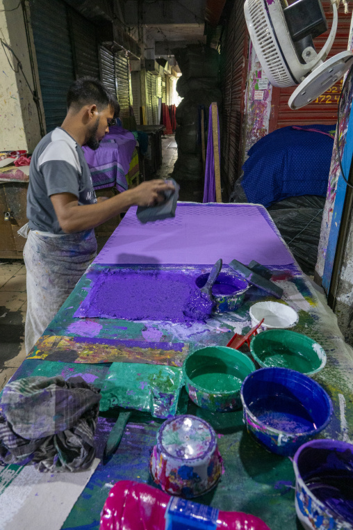 Craftsman hand block-printing purple fabric with wooden stamps i