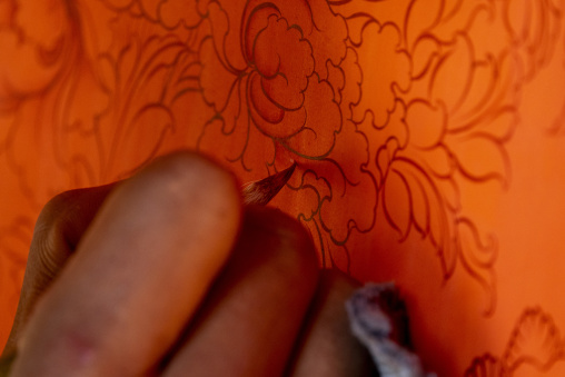 Tibetan artist adding fine gold details to a thangka painting at a workshop, Qinghai Province, Wutun, China
