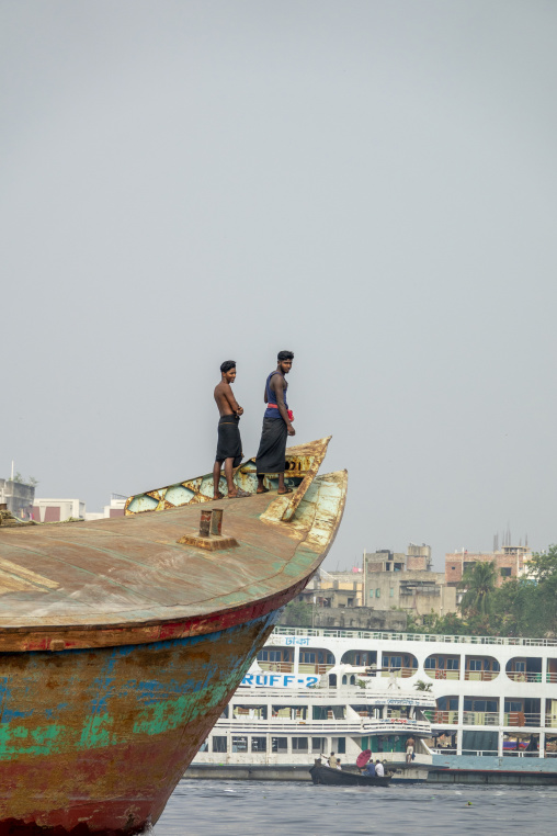 Two young men standing on the bow of a rusty cargo ship on the B
