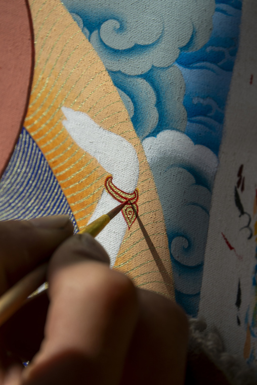Tibetan artist painting clouds and ornaments on a thangka at a workshop, Qinghai Province, Wutun, China