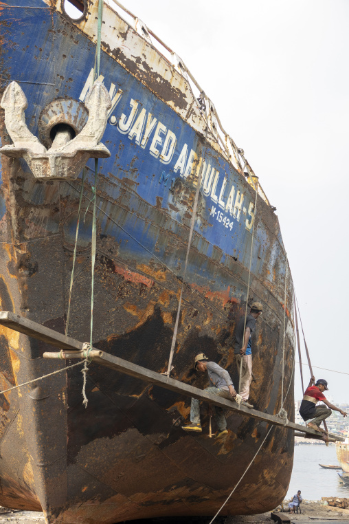 Shipyard workers repairing the rusty hull of the cargo vessel Ja