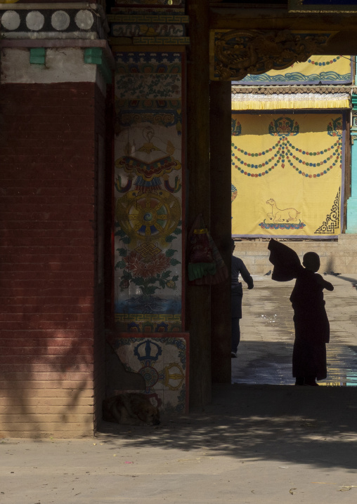 Monk walking through a courtyard at Wutun si monastery, Qinghai Province, Wutun, China