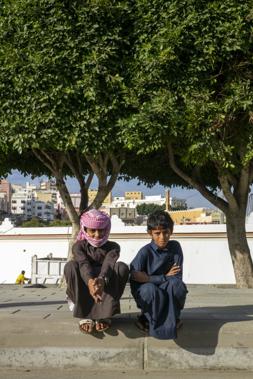 Two boys sitting under a tree in the street, Asir province, Rija