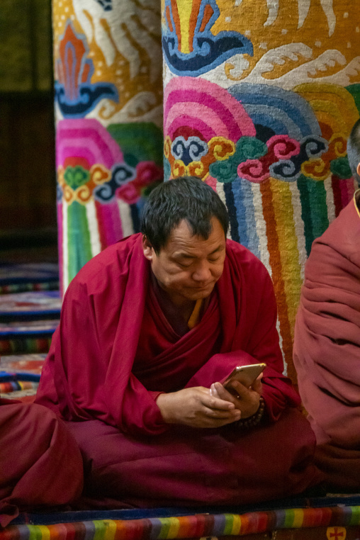 Monk resting between prayers inside Longwu monastery, Tongren County, Longwu, China