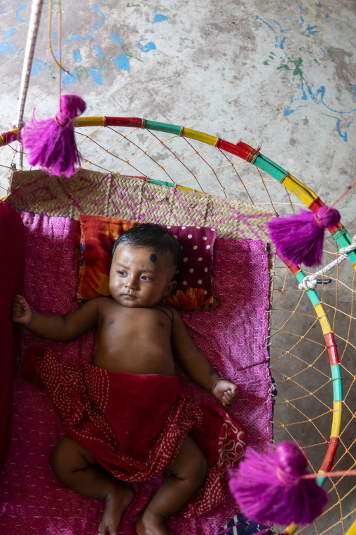 Baby lying in a traditional handmade hanging cradle, Rajshahi Di