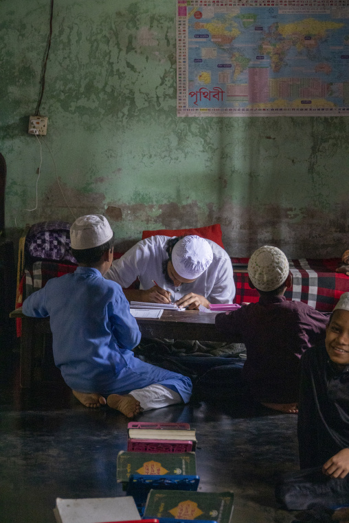 Islamic teacher helping young students with homework at a madras