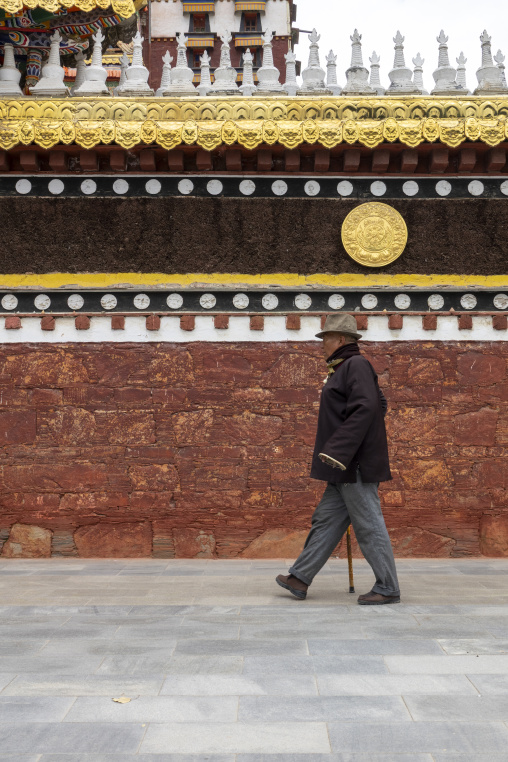 An elderly man walks past a row of stupas at Hezuo monastery, Gansu Province, Hezuo, China