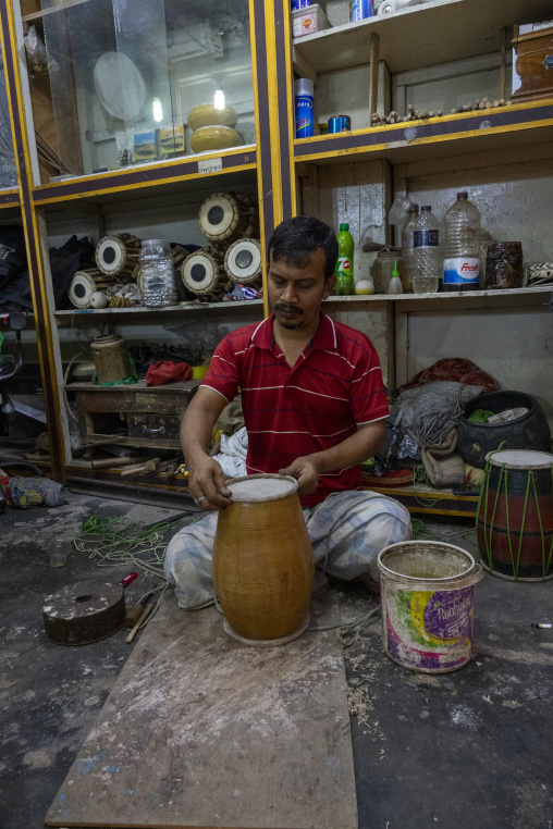 Craftsman assembling a wooden drum in a musical instrument works