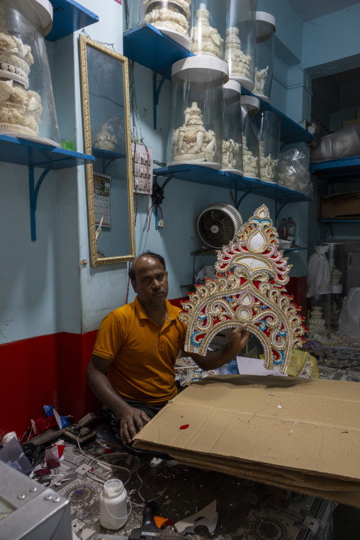 Craftsman displaying an ornate bridal crown decorated with beads