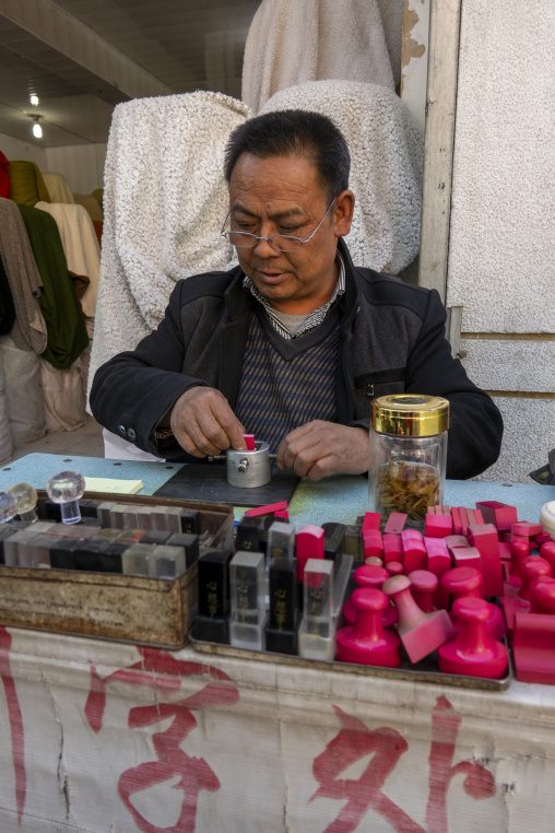 Craftsman carves a traditional Chinese stamp at a street stall, Gansu Province, Linxia, China
