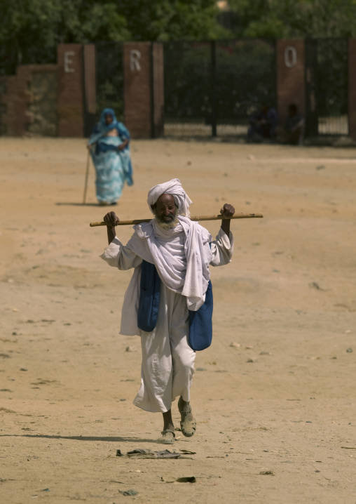 Muslim man walking with a stick on his shoulders, Anseba, Keren, Eritrea