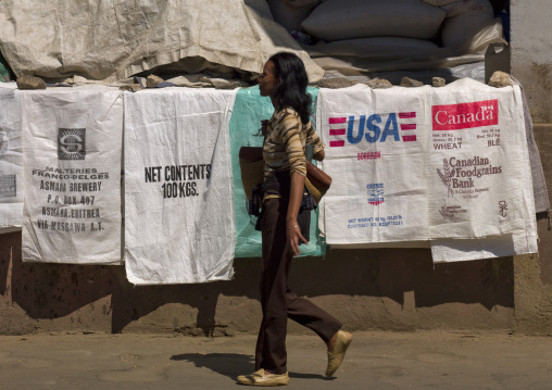 Woman passing in front of food aid bags for sale, Central Region, Asmara, Eritrea