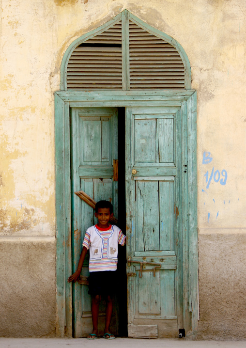 Eritrean boy in front of an old ottoman green house door, Northern Red Sea, Massawa, Eritrea