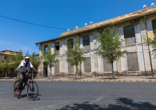 Eritrean man riding a bicycle in front of the old train station, Northern Red Sea, Massawa, Eritrea