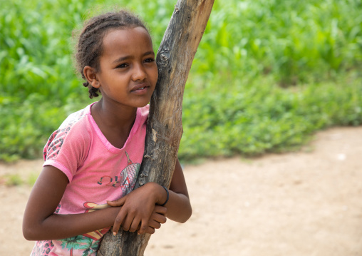 Cute eritrean girl leaning on a trunk tree, Semien-Keih-Bahri, Elabered, Eritrea