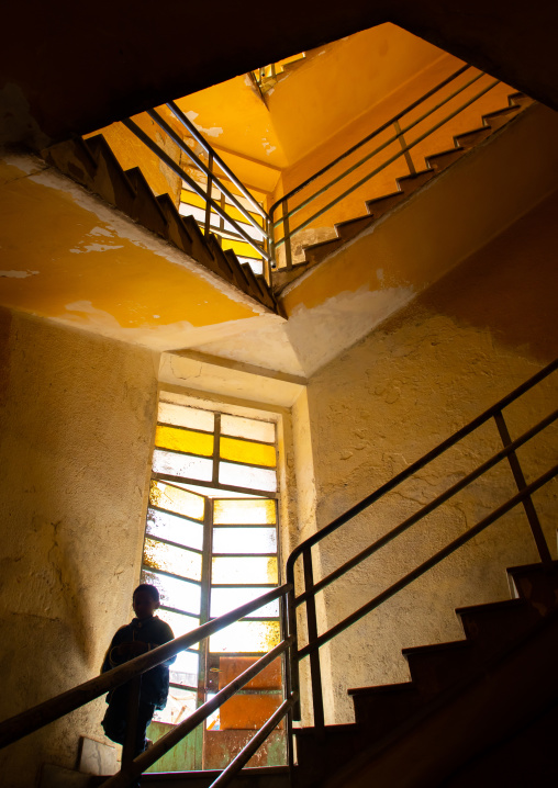 Eritrean boy in an old art deco style stairs from the italian colonial times, Central region, Asmara, Eritrea