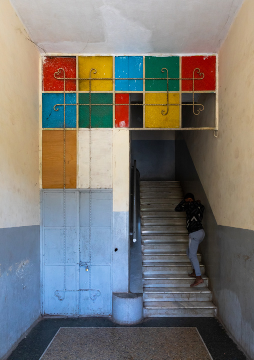 Eritrean girl in an old art deco style stairs from the italian colonial times, Central region, Asmara, Eritrea