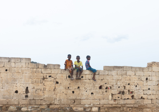 Eritrean boys sit on a wall with bullet holes, Debub, Ghinda, Eritrea