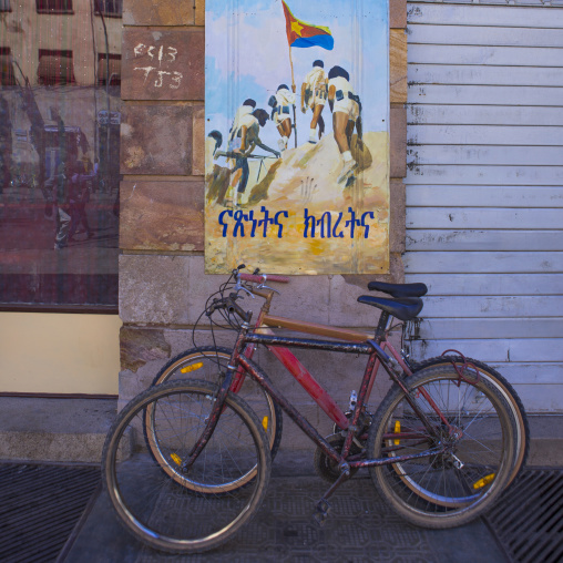 Bicycles in front of a war propaganda poste, Central Region, Asmara, Eritrea