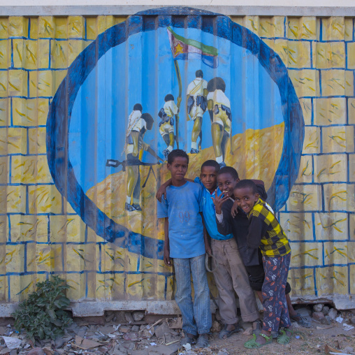 Eritrean boys standing in front of a propaganda painting, Anseba, Keren, Eritrea