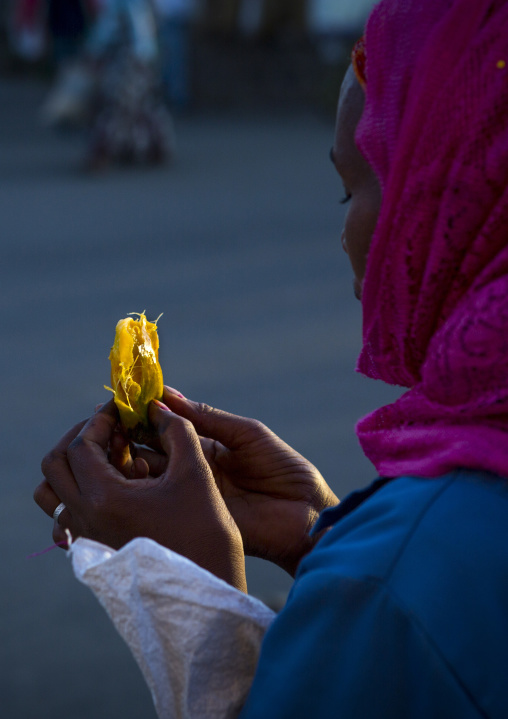 Eritrean woman eating a mango in the street, Central Region, Asmara, Eritrea