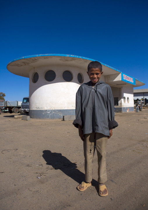 Eritrean boy in front of service station by Carlo Marchi and Carlo Montalbetti, Central Region, Asmara, Eritrea