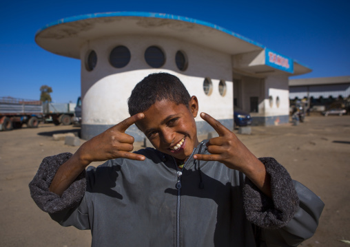 Eritrean boy in front of service station by Carlo Marchi and Carlo Montalbetti, Central Region, Asmara, Eritrea
