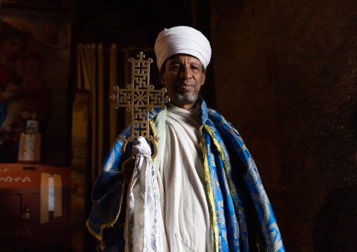 Portrait of an ethiopian orthodox priest holding a cross inside a rock-hewn church, Amhara Region, Lalibela, Ethiopia