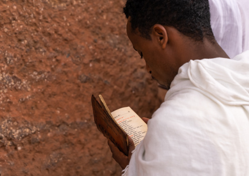 Orthodox pilgrim man reading the Bible, Amhara Region, Lalibela, Ethiopia