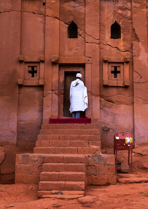 Ethiopian orthodox priest entering a rock-hewn church, Amhara Region, Lalibela, Ethiopia