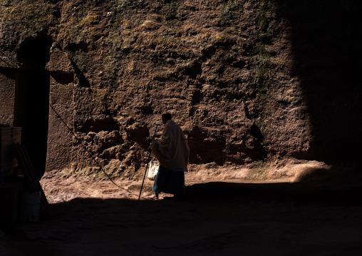 Ethiopian monk walking outside a rock-hewn church, Amhara Region, Lalibela, Ethiopia