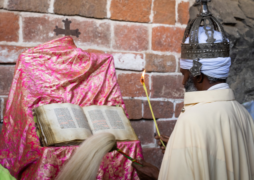 Ethiopian orthodox priest with an old bible in nakuto lab rock church, Amhara Region, Lalibela, Ethiopia
