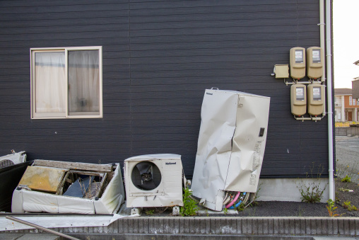 Discarded household appliances outside an abandoned house in the