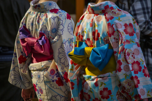 Close-up of two women wearing colorful kimono with ornate obi bo
